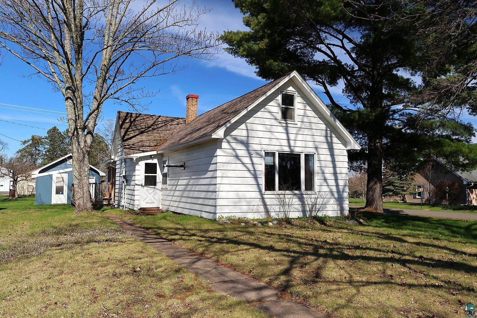 White clapboard siding exterior with a shingled roof and brick chimney