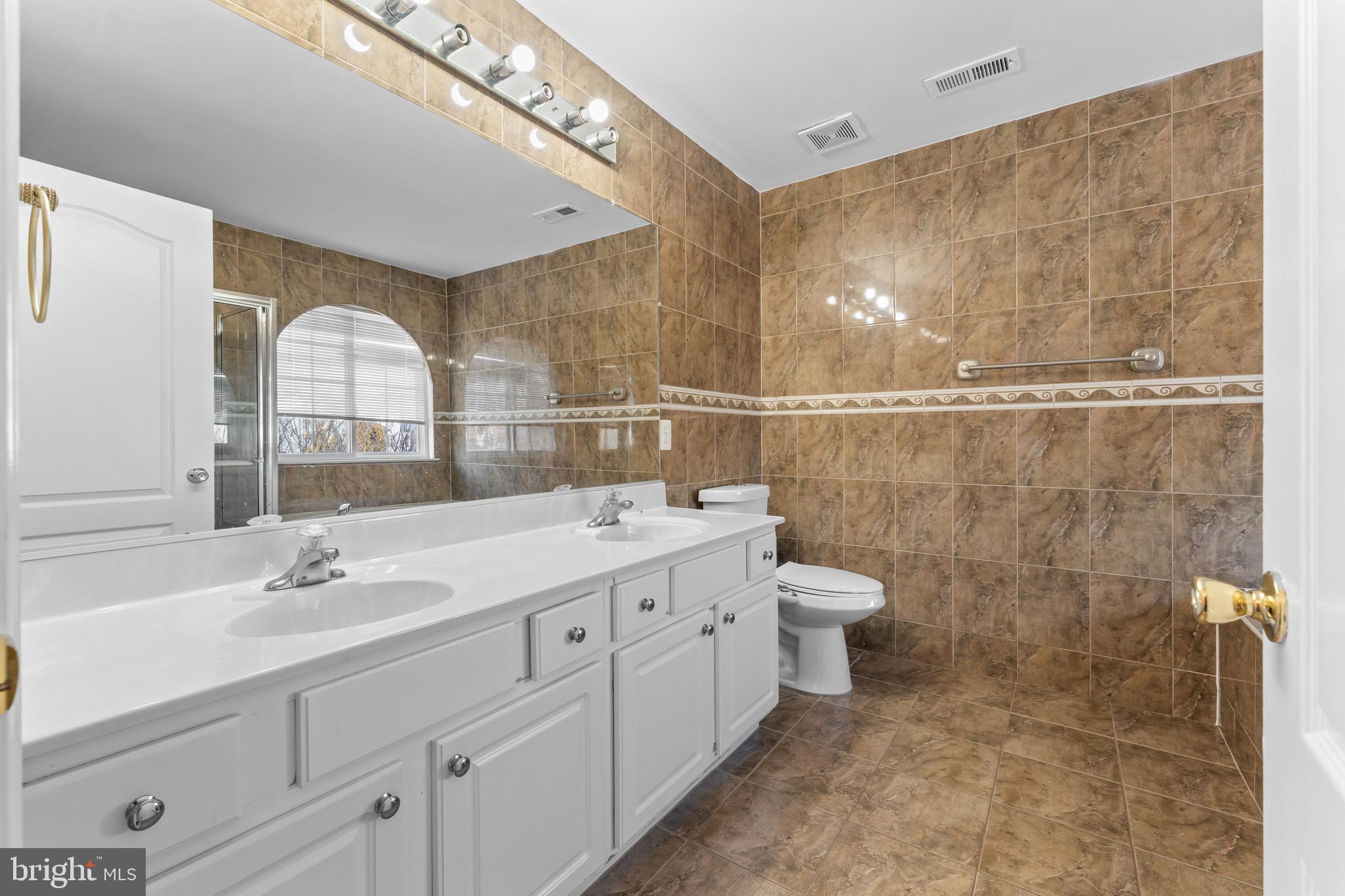 7510 Gilley Terrace Rosedale, MD 21237 - Photo 27 of 46 a bathroom with a double vanity sink toilet and a mirror