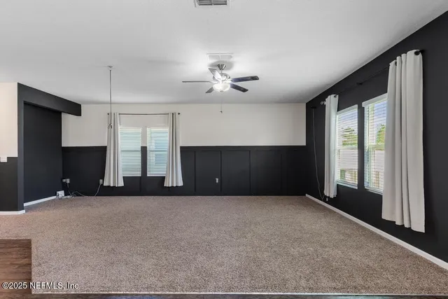 a living room with a large window and ceiling fan