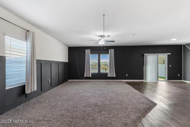 a view of an empty room with wooden floor and window