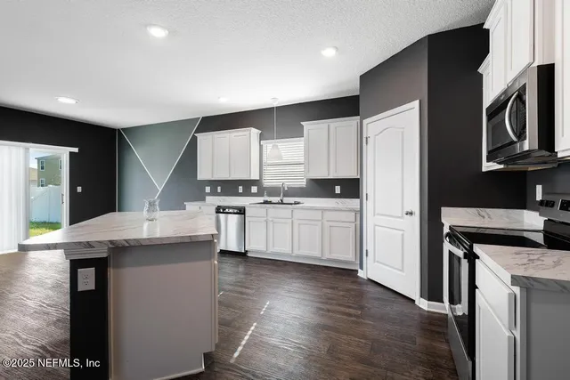 a kitchen with kitchen island granite countertop a sink appliances and cabinets