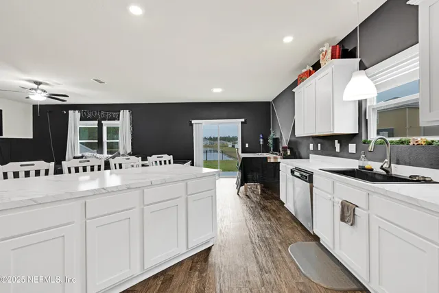 a large white kitchen with kitchen island a stove a sink a refrigerator and cabinets