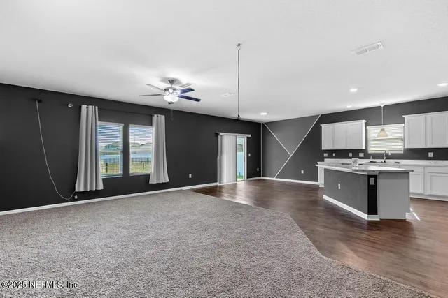 a view of an empty room with a kitchen and a window