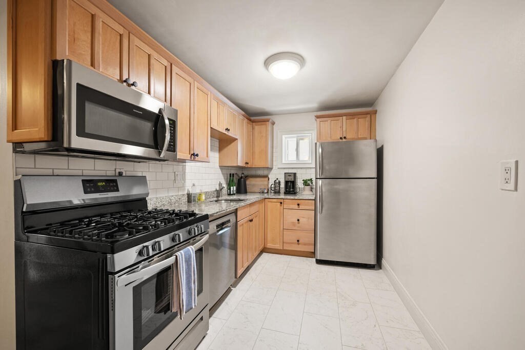 280 E Street, Unit 1 Boston, MA 02127 - Photo 6 of 19 a kitchen with granite countertop a refrigerator stove and microwave
