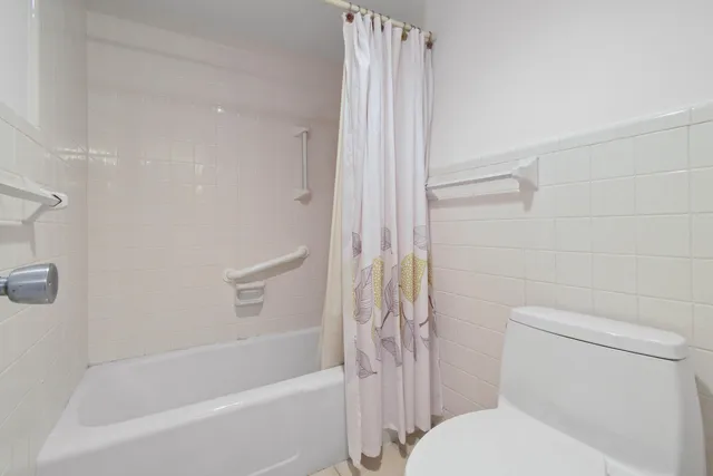 a white toilet sitting next to a bath tub