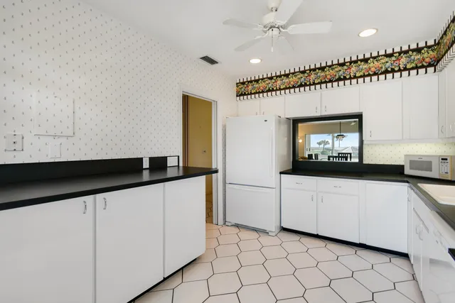 a kitchen with granite countertop white cabinets and white appliances