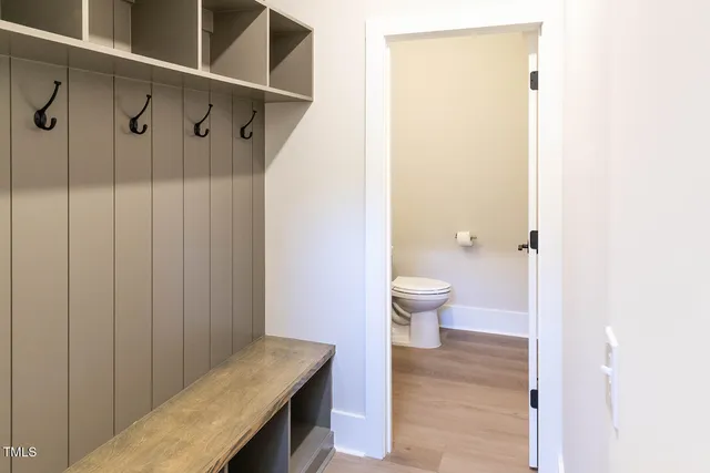 a large kitchen with a refrigerator a sink dishwasher a stove and white cabinets with wooden floor