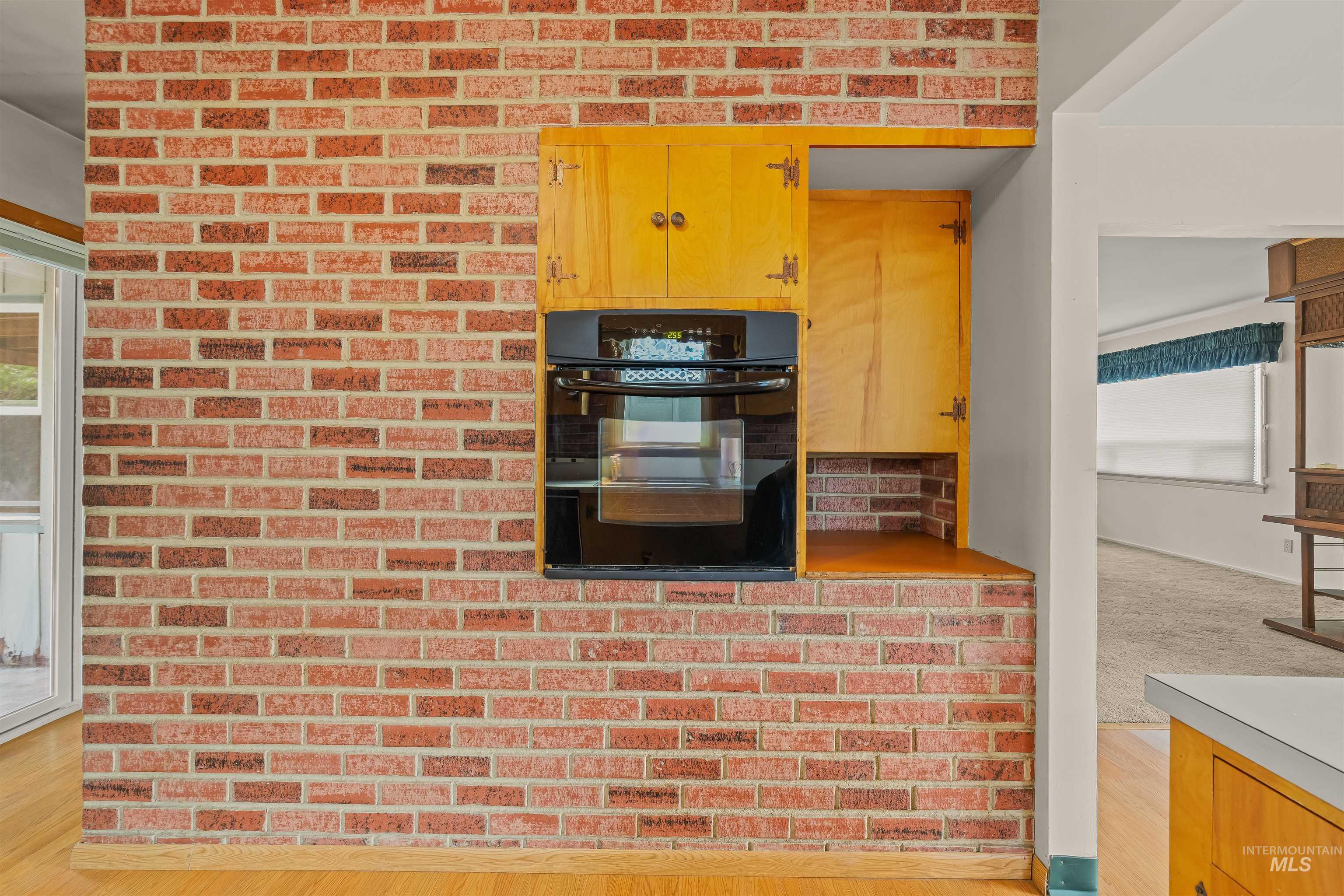 1663 9th Avenue Lewiston, ID 83501 - Photo 12 of 36 Brick accent wall featuring a built-in oven, integrated wooden cabinetry, and wood-finish flooring