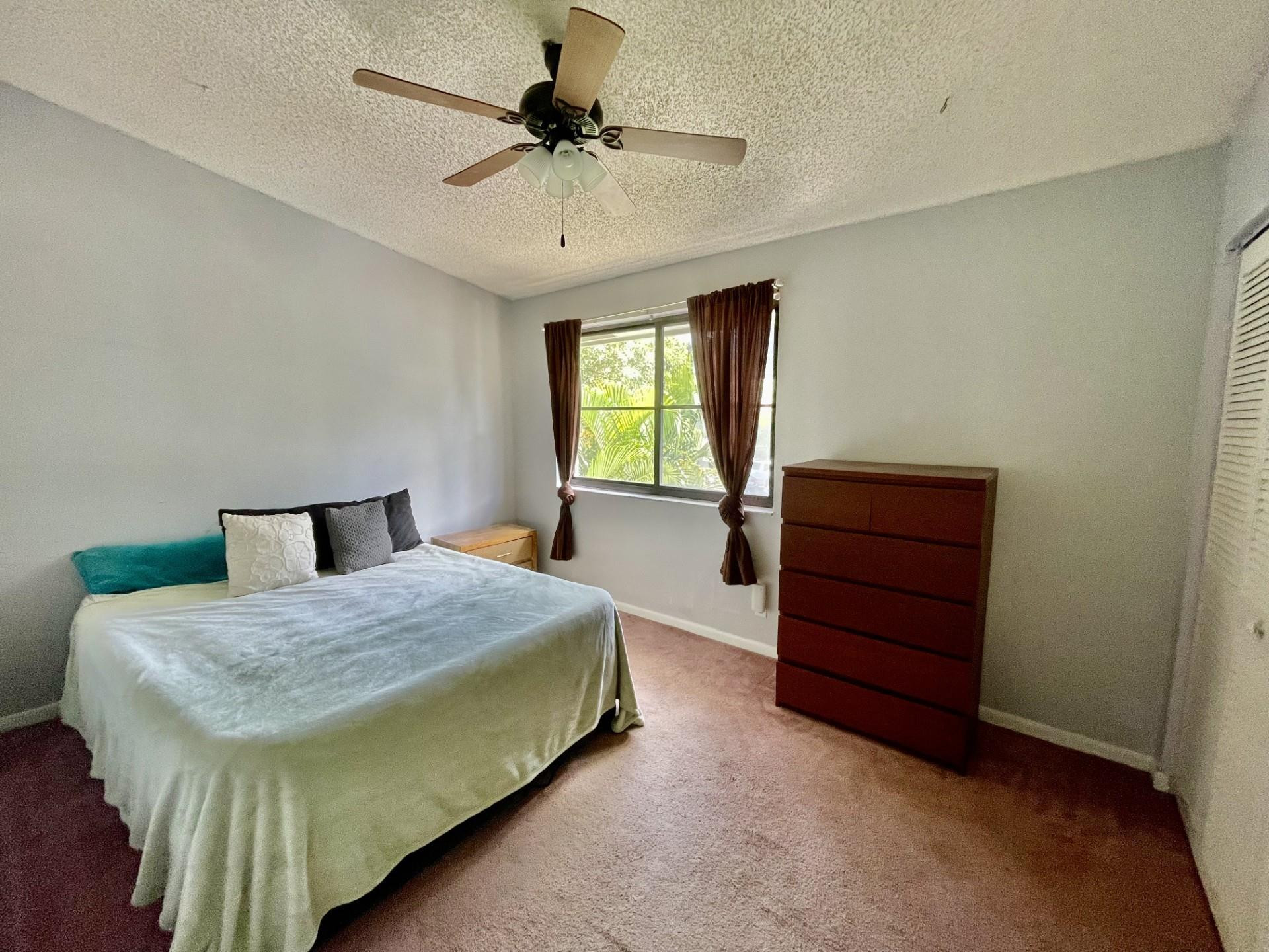 9787 Riverside Drive, Unit 624 Coral Springs, FL 33071 - Photo 16 of 21 a bedroom with a bed and a chandelier