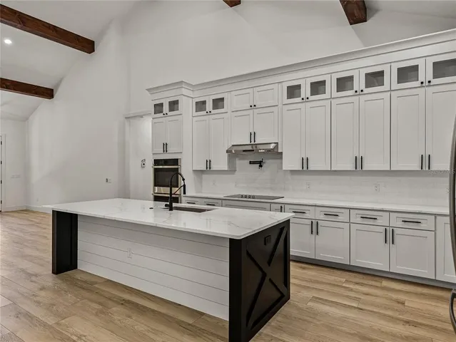 a large kitchen with stainless steel appliances kitchen island granite countertop a stove a sink dishwasher and a wooden cabinets with wooden floor