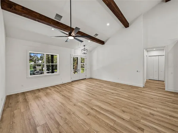 a view of an empty room with window and wooden floor