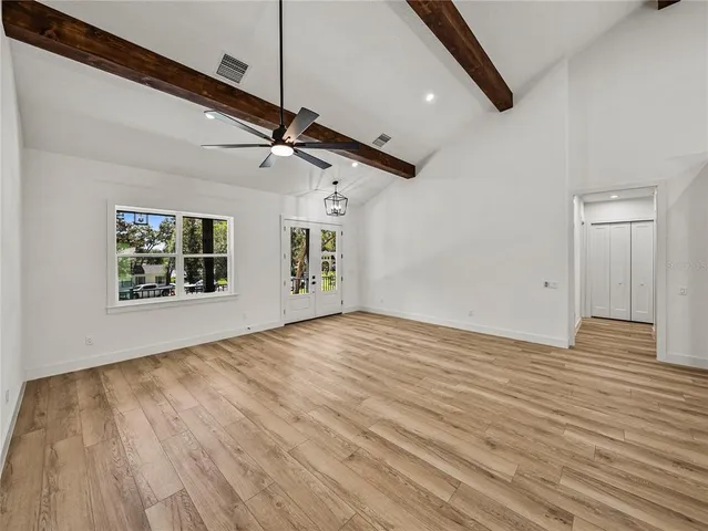 a view of an empty room with window and wooden floor