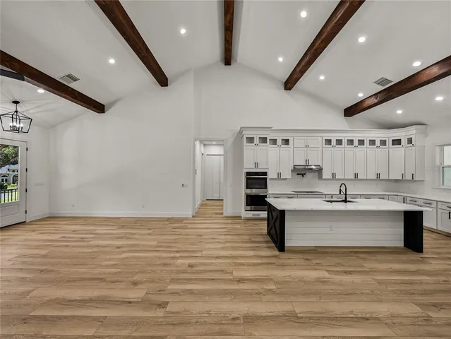a view of kitchen with stainless steel appliances granite countertop a stove and a sink