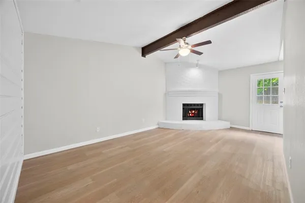a view of an empty room with a fireplace and a window