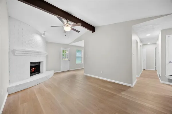 a view of an empty room with chandelier fan and fire place