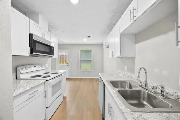 a kitchen with granite countertop a sink a stove and cabinets