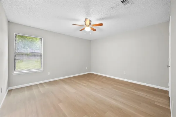 an empty room with windows and fan