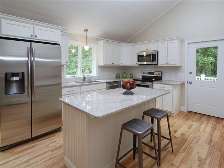 537 Scraggy Neck Road Cataumet, MA 02534 - Photo 14 of 33 a kitchen with stainless steel appliances granite countertop a sink a stove a refrigerator cabinets and a dining table with wooden floor