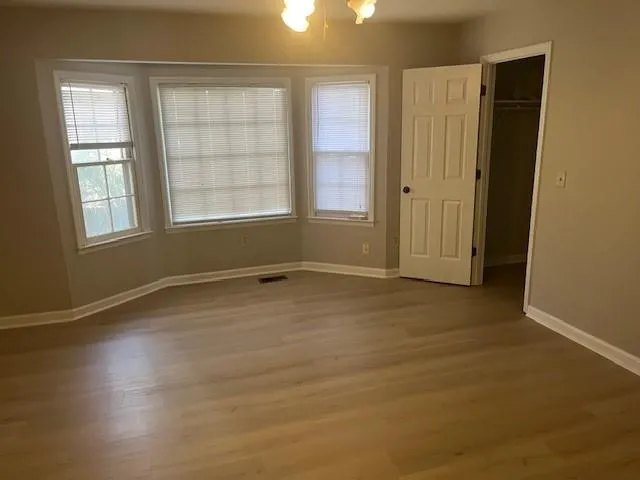 an empty room with wooden floor and windows