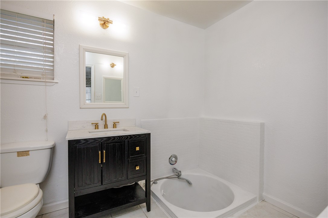 4029 Congressional Drive Corpus Christi, TX 78413 - Photo 31 of 34 a bathroom with a toilet a sink a mirror and vanity
