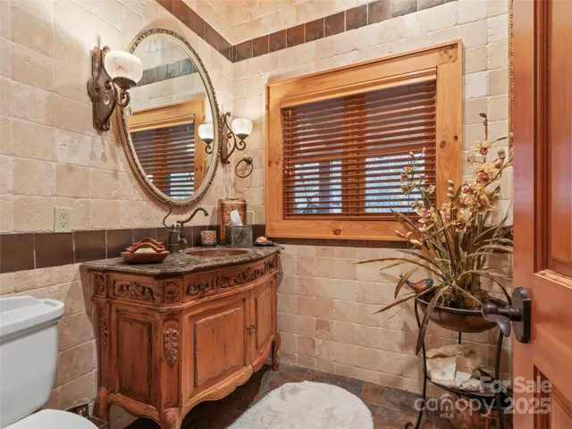 a bathroom with a granite countertop sink a mirror a toilet and a window