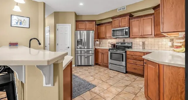 a kitchen with stainless steel appliances granite countertop a stove top oven a sink dishwasher and a refrigerator