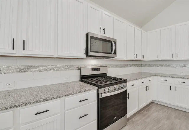 a kitchen with granite countertop white cabinets and stainless steel appliances
