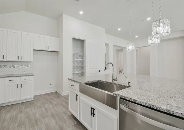 a kitchen with granite countertop a sink and white cabinets