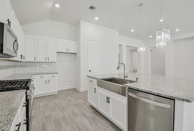a kitchen with granite countertop a sink a stove refrigerator and cabinets