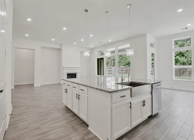 a large white kitchen with granite countertop a large counter top and sink