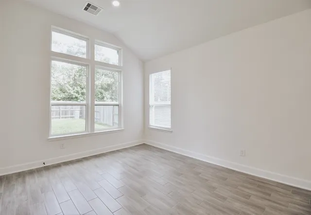 an empty room with wooden floor and windows