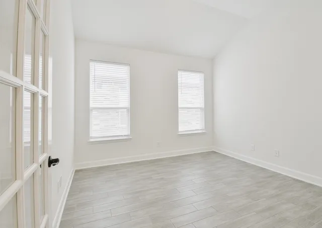 an empty room with wooden floor and windows