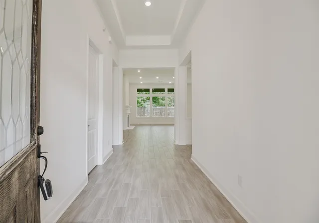 a view of a hallway with wooden floor and a bathroom