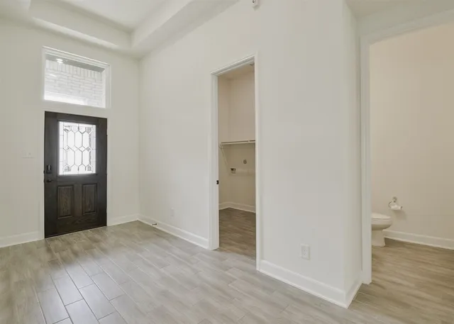 a view of an empty room with wooden floor and a window