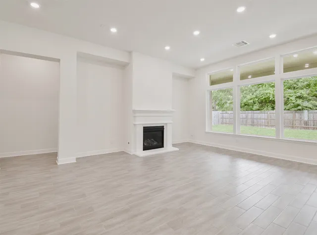 an empty room with wooden floor and a fireplace