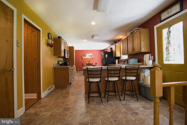 a kitchen with stainless steel appliances granite countertop a refrigerator a sink dishwasher a stove and white cabinets with wooden floor