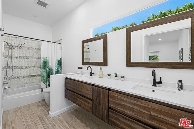 a bathroom with a double vanity sink mirror and shower