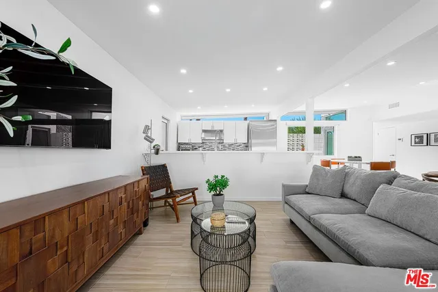 a living room with furniture kitchen view and a potted plant