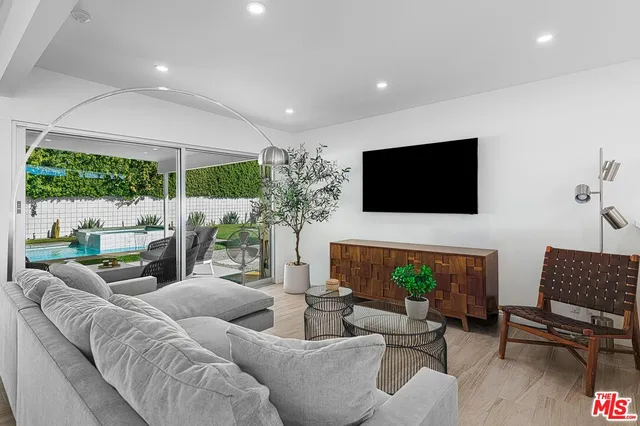 a living room with furniture a flat screen tv and a floor to ceiling window