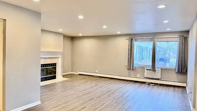an empty room with wooden floor fireplace and windows