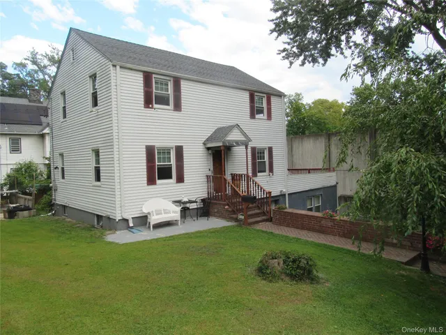 a front view of a house with garden and chairs