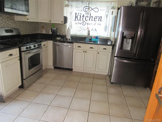a kitchen with granite countertop a refrigerator a stove a sink and dishwasher