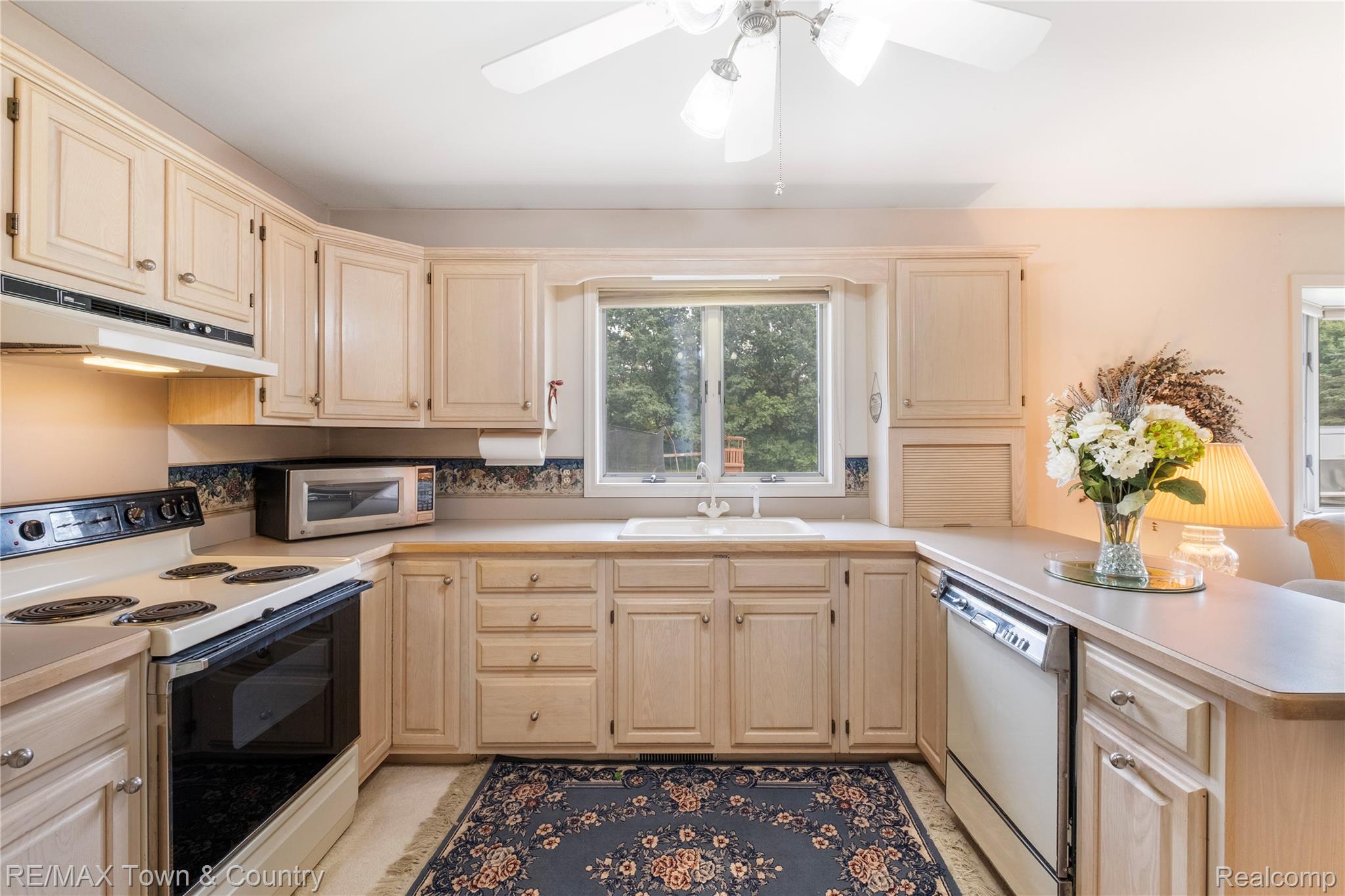 5464 North Seymour Road Flushing, MI 48433 - Photo 23 of 45 U-shaped kitchen featuring light wood-finish cabinetry, a double basin sink, and a ceiling fan with integrated lighting