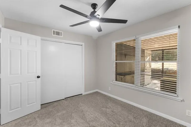 a view of an empty room with a window and a ceiling fan