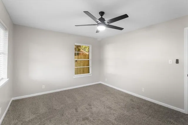 an empty room with a window and ceiling fan