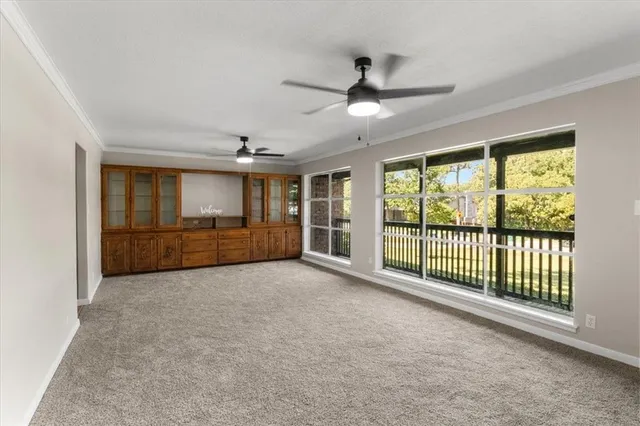 a view of an empty room with a window and a ceiling fan