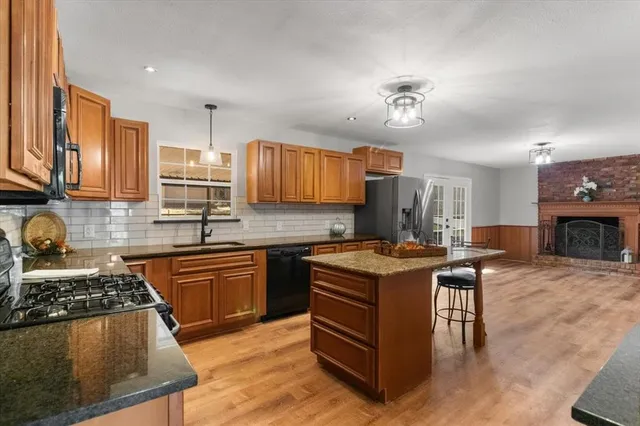a kitchen with stainless steel appliances granite countertop a stove top oven a sink dishwasher and cabinets with wooden floor
