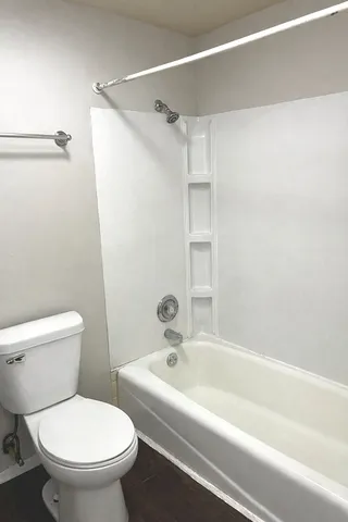 a white toilet sitting next to a bath tub