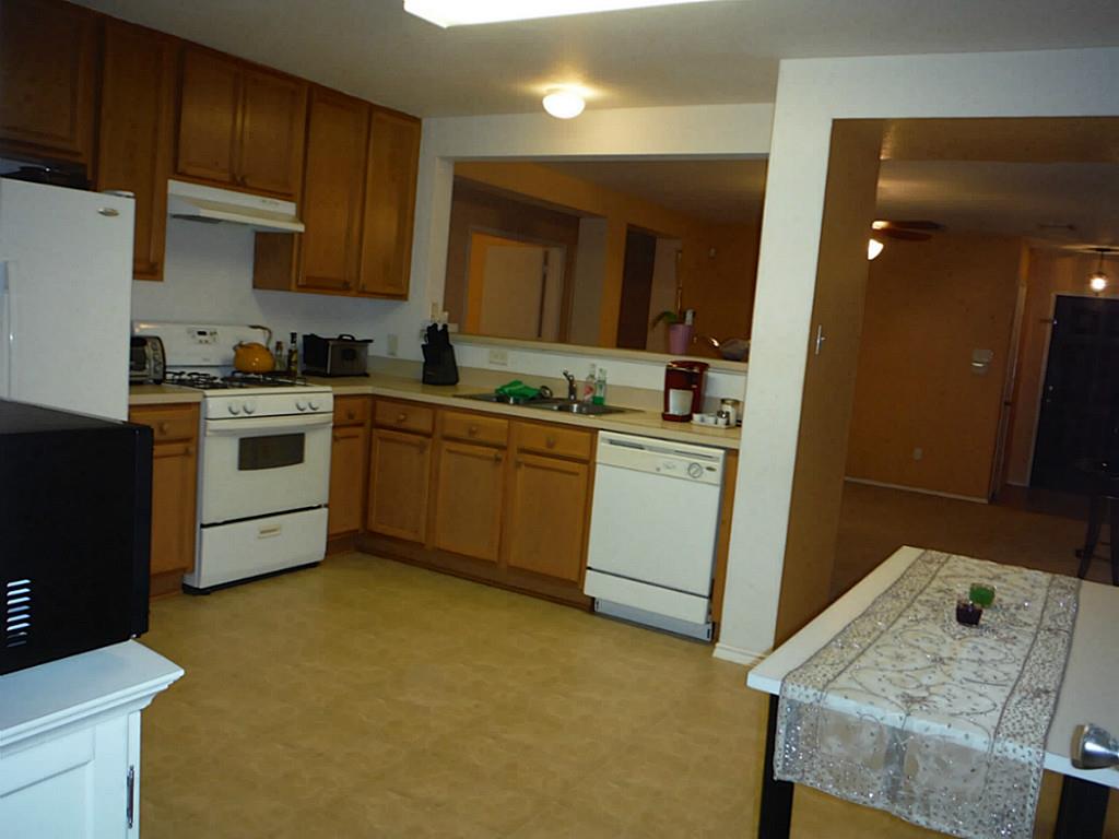 3142 Aspen Fair Trail Spring, TX 77389 - Photo 4 of 22 This photo showcases a cozy kitchen with wooden cabinetry, a gas stove, and a dishwasher. The space is open and well-lit, featuring a functional layout with an adjacent dining area partially visible.