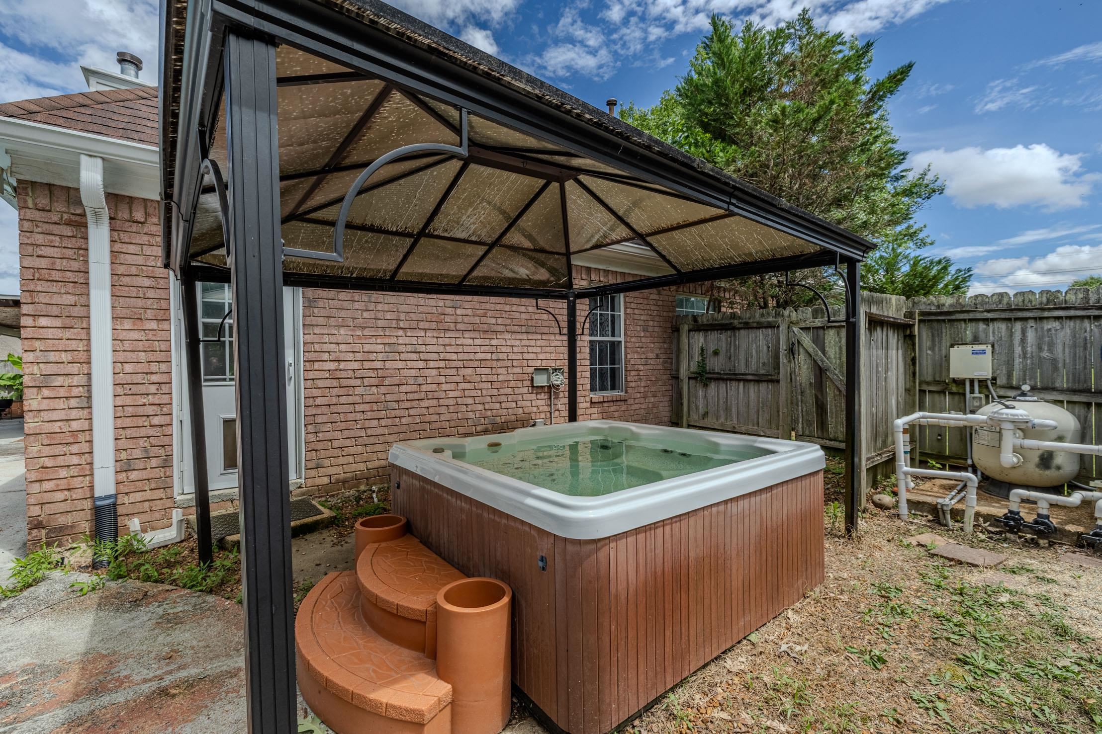 96 Berryfield Cove Collierville, TN 38017 - Photo 32 of 39 Outdoor spa featuring a brown wood-finish exterior and integrated steps, sheltered by a black metal gazebo